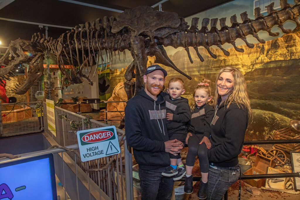 Colby Wilson and family in front of Dinosaur Skeleton